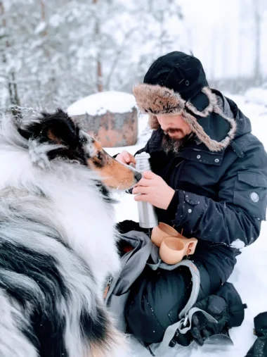 Meistä 18 mies syö eväitä talvella koiransa kanssa ulkona