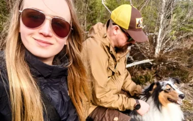 Meistä 13 mies, nainen ja koiraa istuu kaatuneen puun päällä