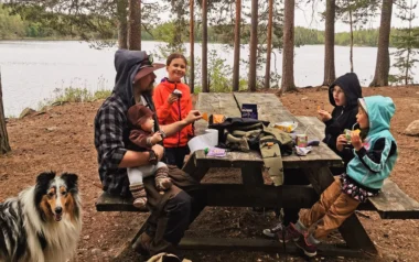 Meistä 2 perhe syö eväitä rannassa pöydän äärellä