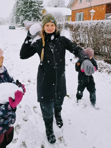 Meistä 40 perhe leikkii lumessa, nainen heittää juuri lumipalloa kameraa päin